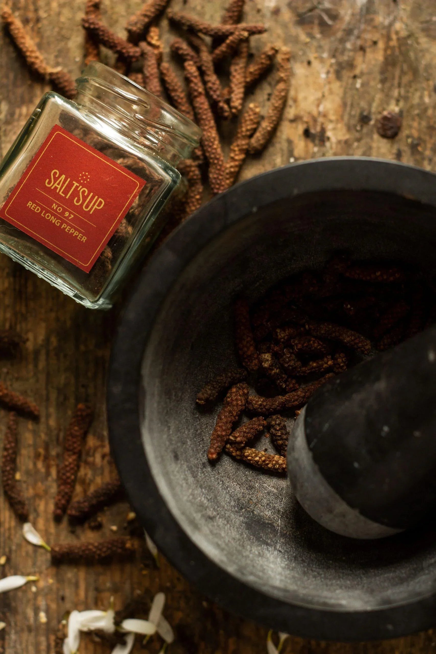 Red long pepper in a glass jar and mortar with pestle on rustic wooden table