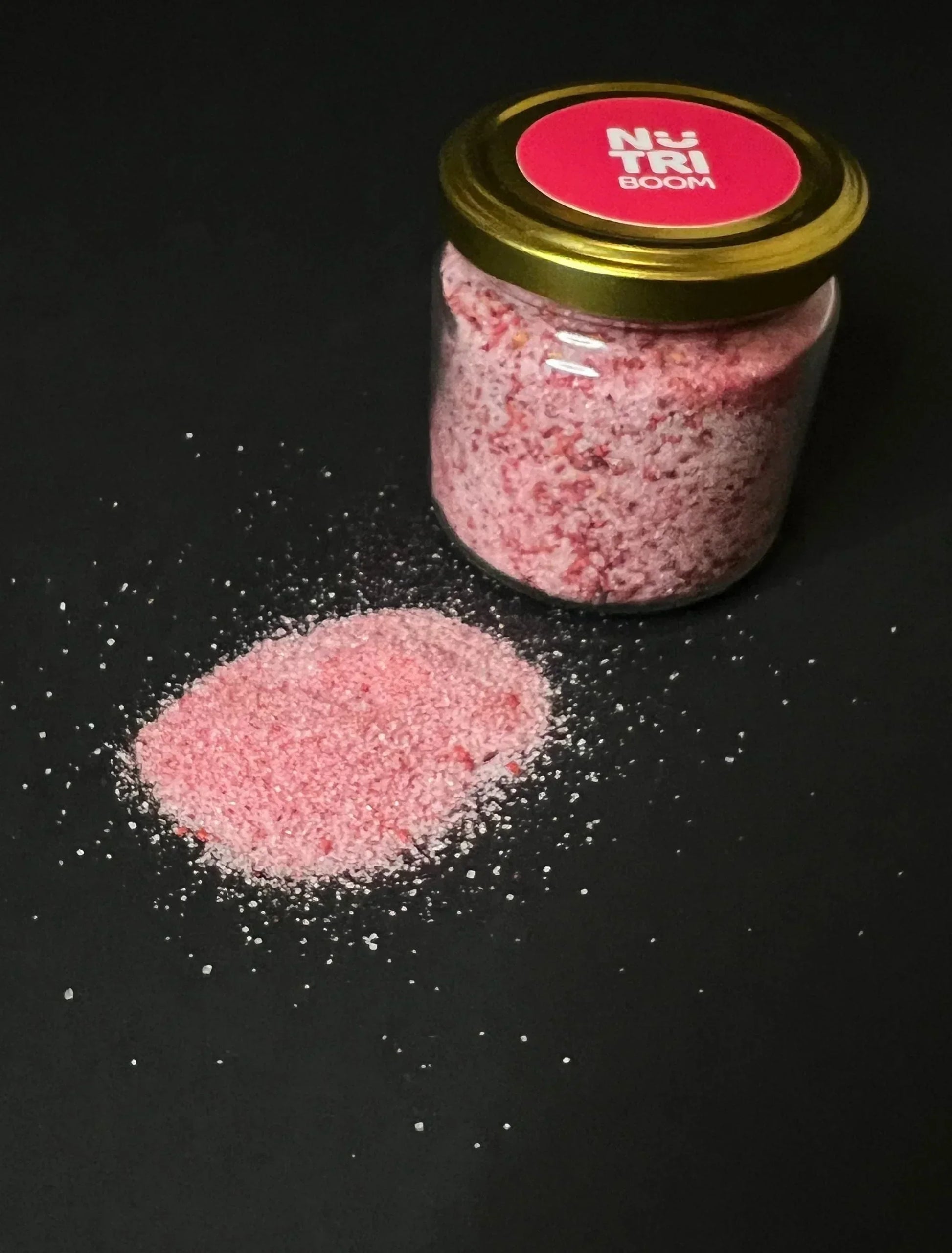 Glass jar of raspberry sugar with pink crystals and a sprinkle of freeze-dried raspberries