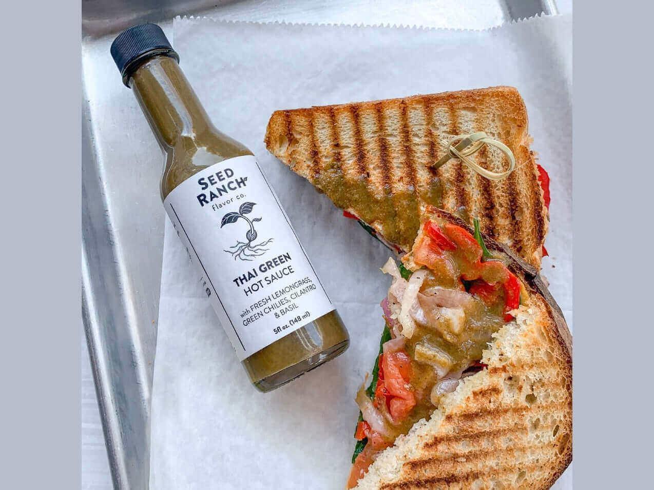 Grilled vegetable sandwich with Thai green hot sauce on a tray, artisan lunch option