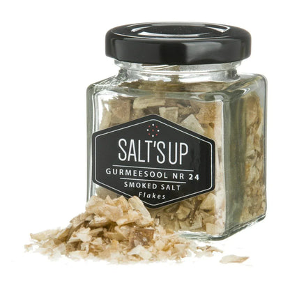 Glass jar of smoked salt flakes with label and salt flakes spilled in front